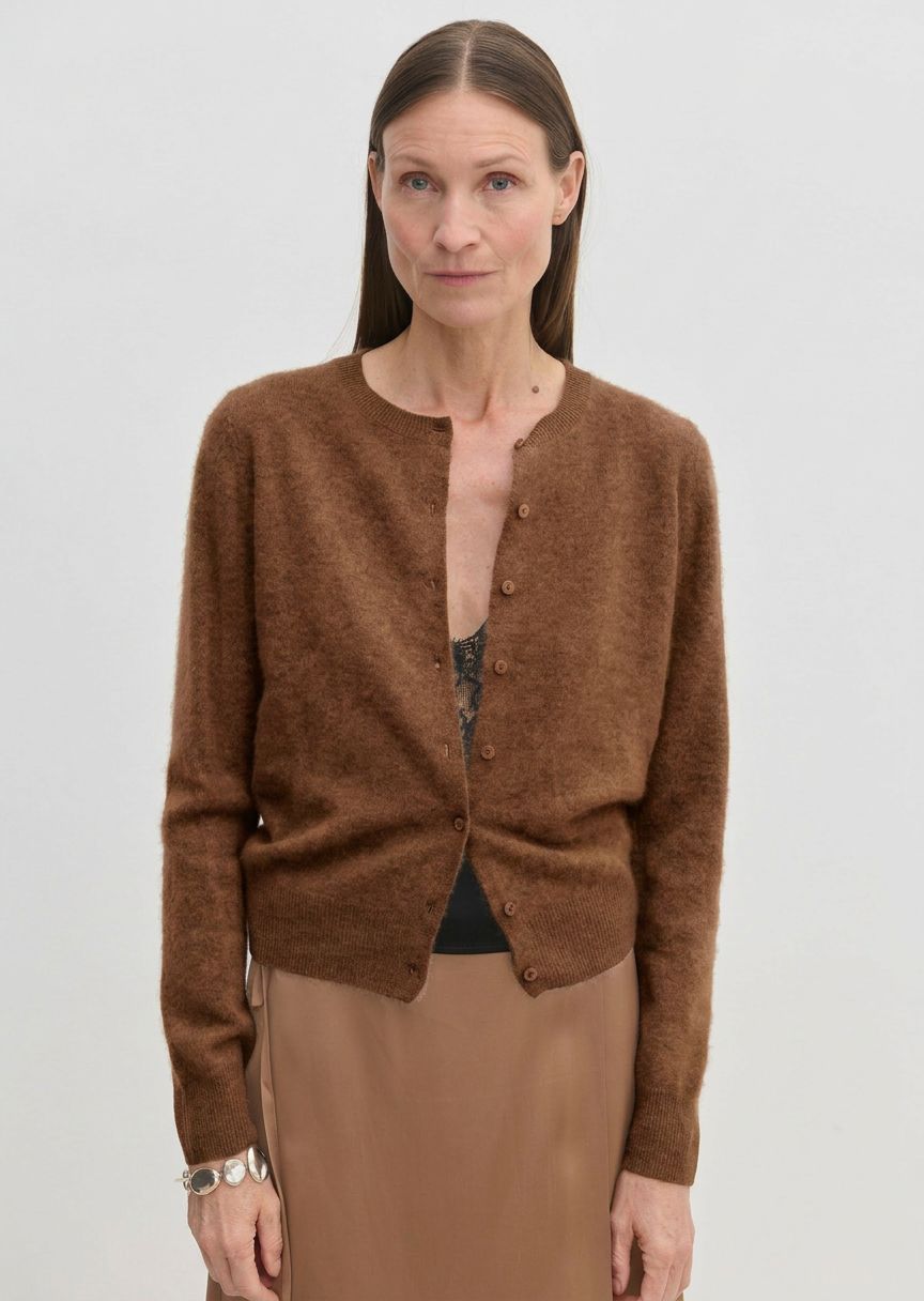 A brown brushed wool Roselle Knit Cardigan by Herskind ApS worn over a black lace camisole and a tan skirt.