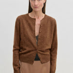 A brown brushed wool Roselle Knit Cardigan by Herskind ApS worn over a black lace camisole and a tan skirt.