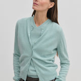 A woman wears a light blue, brushed wool Roselle Knit Cardigan by Herskind ApS over a matching V-neck sweater.