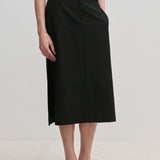A person wearing a white top and the black Collin Mid waist Skirt, a midi-length style with a front seam and straight silhouette.