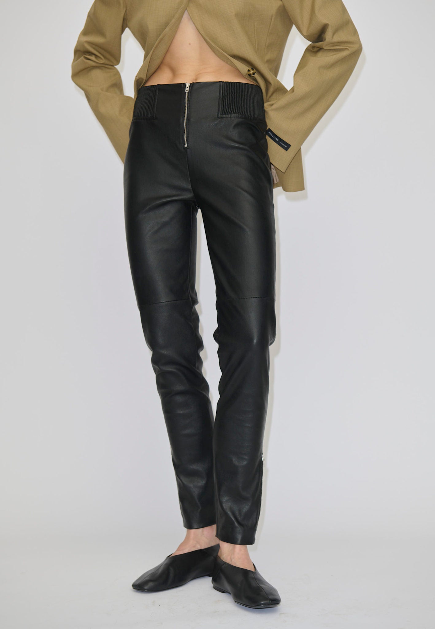 Person wearing black Barbie Leather Leggings with a front zipper and a tan blazer.