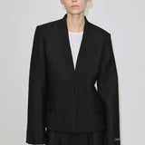 A person wears a black, single-button, fitted Higgins Fitted Blazer by Herskind ApS with a notched neckline over a white top.