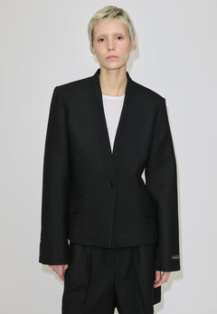 A person wears a black, single-button, fitted Higgins Fitted Blazer by Herskind ApS with a notched neckline over a white top.