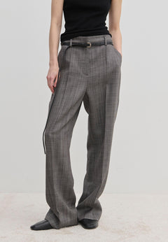 Herskind ApS Cambs Mid waist Pants in grey with a patterned design, wide leg silhouette, black belt, and pressed front creases, worn with a black top and black shoes.
