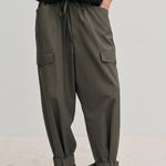 Olive green Maddie Mid waist Baggy Pants with a relaxed, baggy fit, featuring a drawstring waist, side pockets, and buckled straps at the ankles.