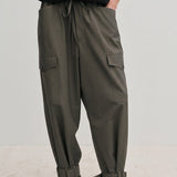 Olive green Maddie Mid waist Baggy Pants with a relaxed, baggy fit, featuring a drawstring waist, side pockets, and buckled straps at the ankles.