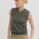 A person wearing an olive green Herskind ApS Fabien Knit Vest with a V-neckline.
