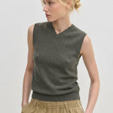 A person wearing an olive green Herskind ApS Fabien Knit Vest with a V-neckline.