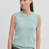 A woman wears a light blue V-neck Fabien Knit Vest by Herskind ApS over dark trousers.