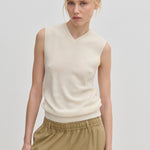 A model wearing a cream-colored Fabien Knit Vest and tan trousers.