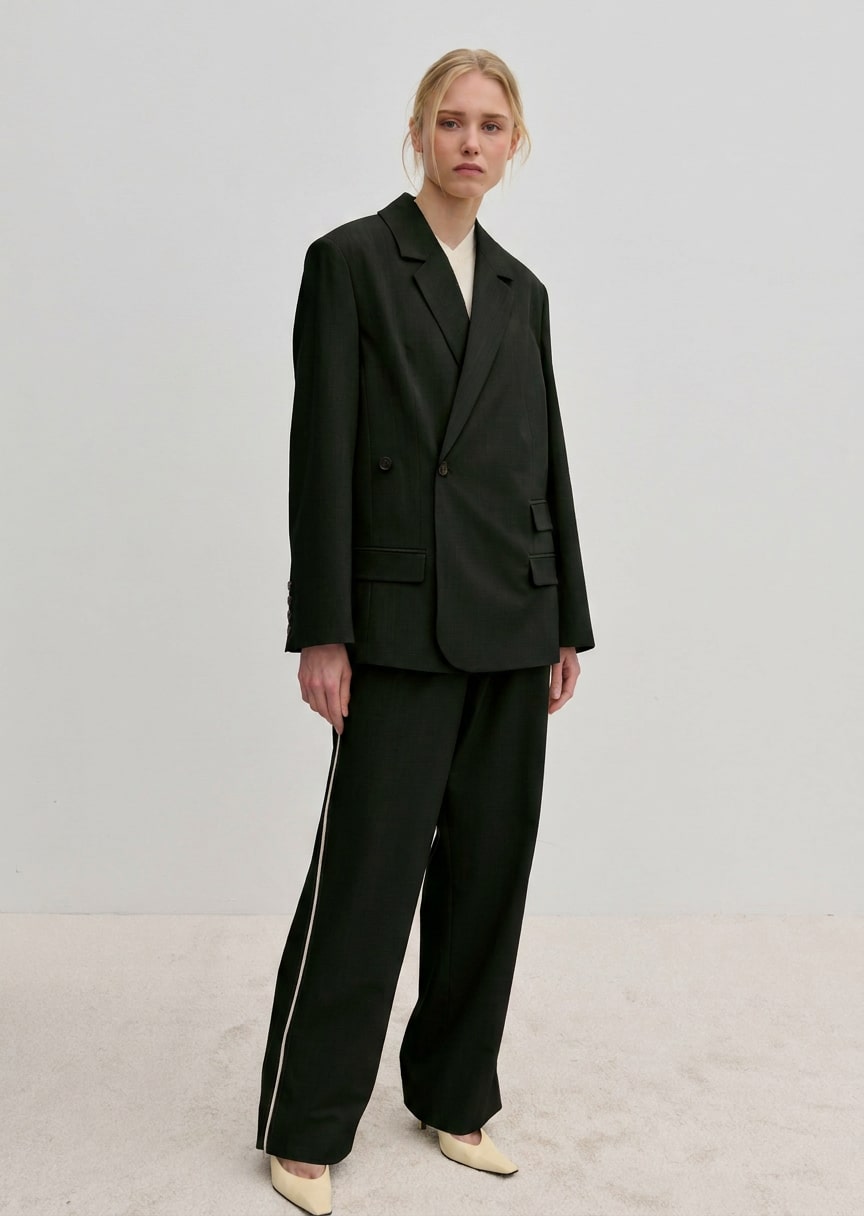 A person wearing a structured, double-breasted Herskind ApS Amalfi Regular Blazer and loose trousers with side stripes.