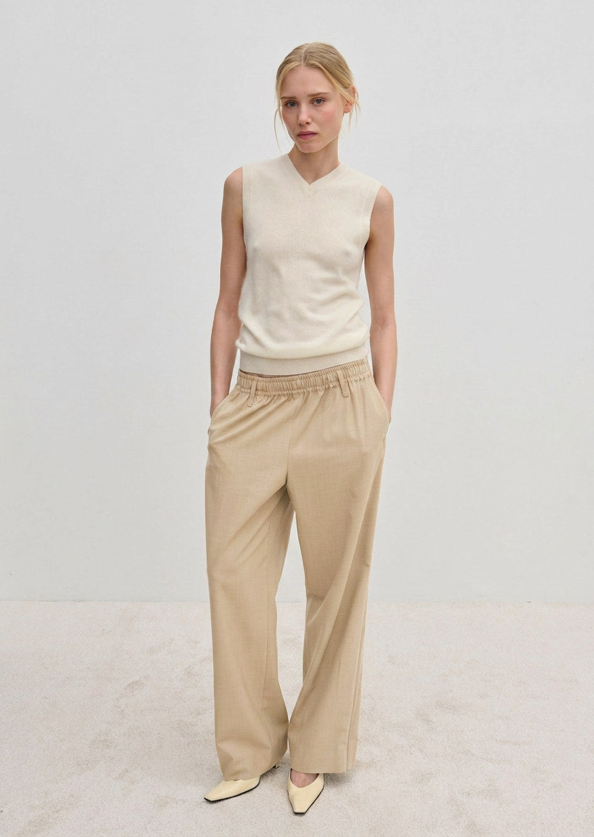 A person wearing a sleeveless V-neck sweater and Davi Mid waist Pants, which are mid-waist, wide-leg trousers with an elasticated waistband.
