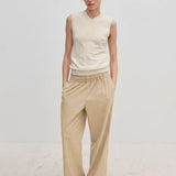 A person wearing a sleeveless V-neck sweater and Davi Mid waist Pants, which are mid-waist, wide-leg trousers with an elasticated waistband.