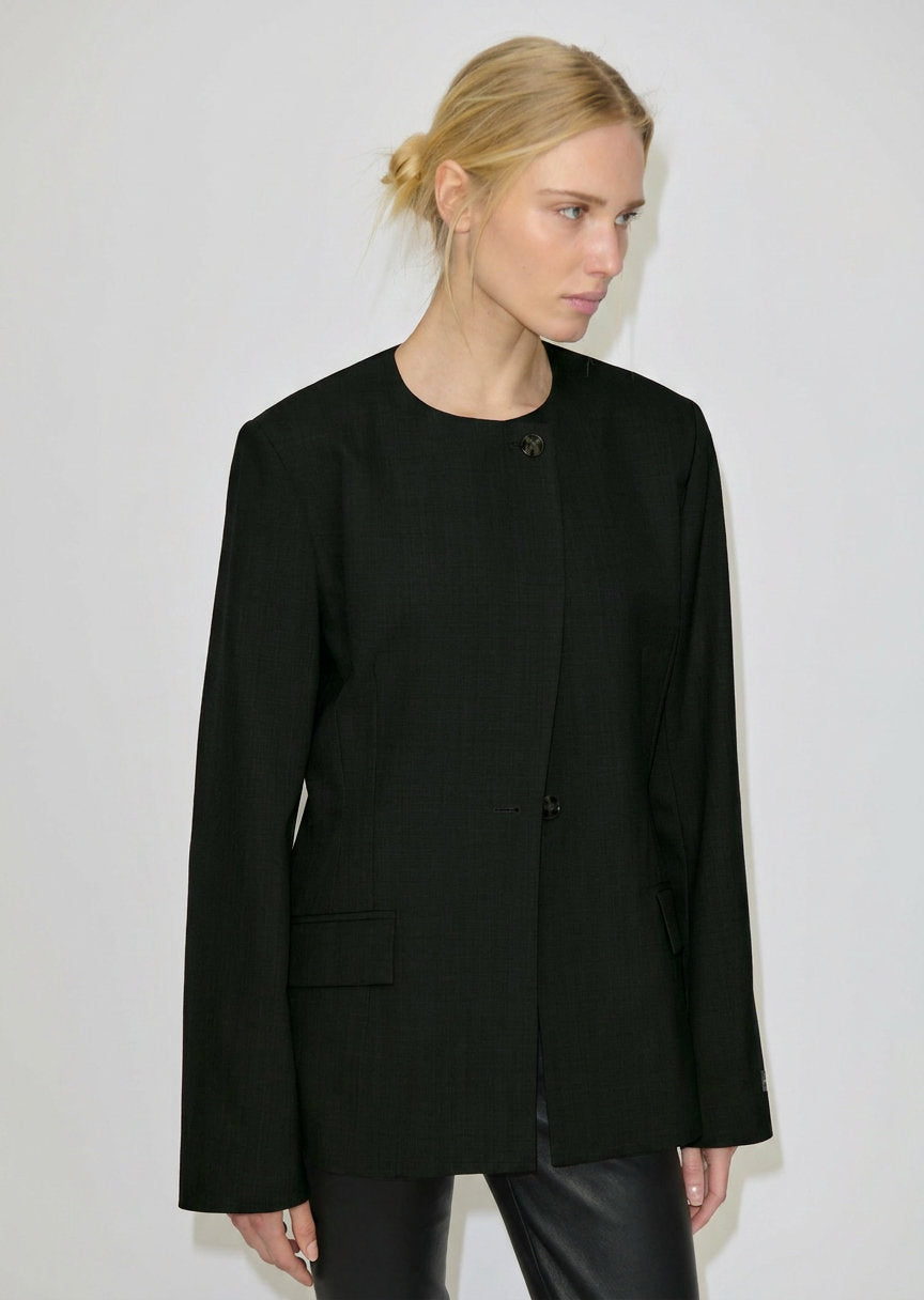 A woman wearing a Robyn Fitted Blazer, featuring a collarless tailored design with a buttoned front and structured shoulders.