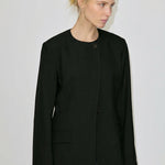 A woman wearing a Robyn Fitted Blazer, featuring a collarless tailored design with a buttoned front and structured shoulders.