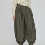 Herskind ApS Zeth High Waist Pants in olive green, featuring a high-waisted, relaxed, balloon-leg silhouette with gathered cuffs, worn with a cream sweater and black heeled mules.