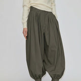 Herskind ApS Zeth High Waist Pants in olive green, featuring a high-waisted, relaxed, balloon-leg silhouette with gathered cuffs, worn with a cream sweater and black heeled mules.