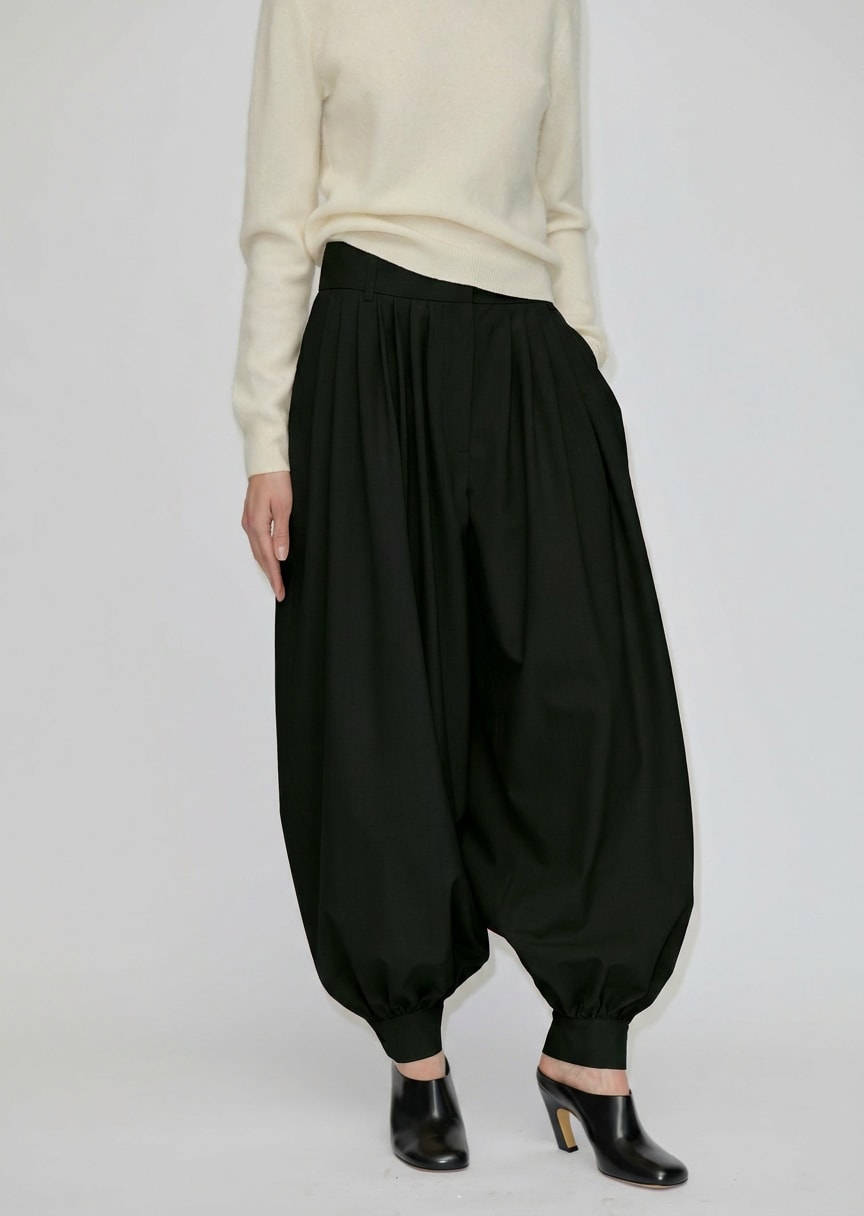 A person wearing black Zeth High Waist Pants with a balloon-leg silhouette, gathered hem, and black heeled mules.