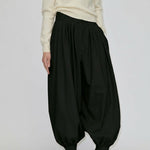 A person wearing black Zeth High Waist Pants with a balloon-leg silhouette, gathered hem, and black heeled mules.