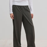 Person wearing dark gray Pinky Mid waist pants with a wide-leg fit and a white long-sleeved shirt.