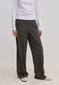 Person wearing dark gray Pinky Mid waist pants with a wide-leg fit and a white long-sleeved shirt.