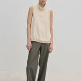 A person wearing a sleeveless cream-colored mock-neck top and Herskind ApS Ivano Mid waist Pants in grey.