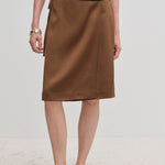 A brown knee-length A-line Emmy Wrap Skirt by Herskind ApS, worn with a black top and black slip-on shoes.