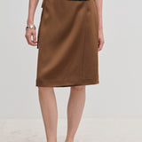 A brown knee-length A-line Emmy Wrap Skirt by Herskind ApS, worn with a black top and black slip-on shoes.