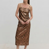 A person wearing a bronze sequined camisole top and the matching Anda Skirt, paired with black flat shoes.