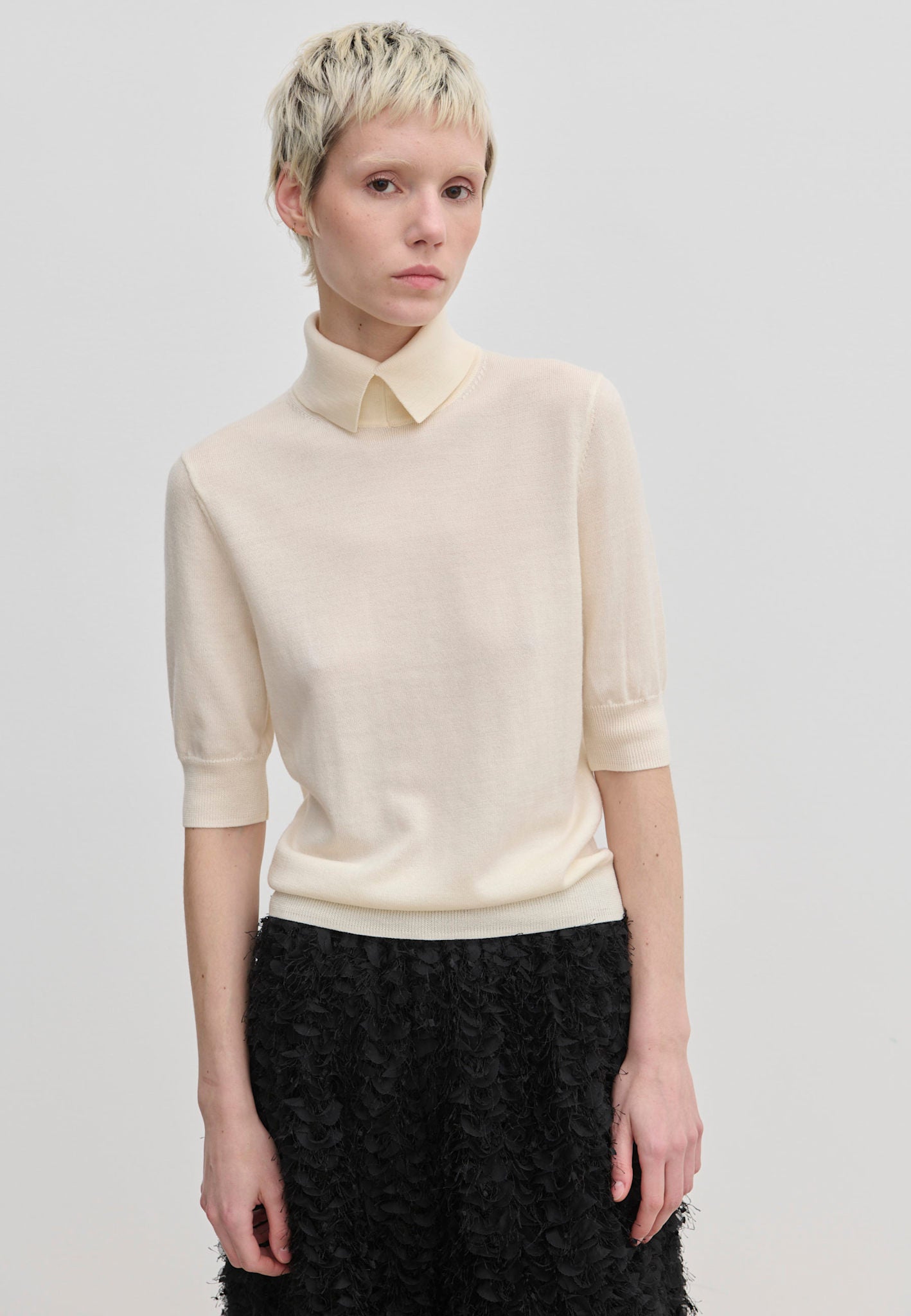 Cream-colored Perry Knit Blouse by Herskind ApS, featuring short sleeves and a pointed collar in merino wool.