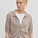 A beige, relaxed-fit Kaspar Knit Polo by Herskind ApS worn unbuttoned over a white t-shirt.