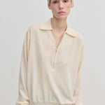 Agatha Knit Blouse by Herskind ApS in a cream-colored fine-gauge knit with a half-zip neckline.