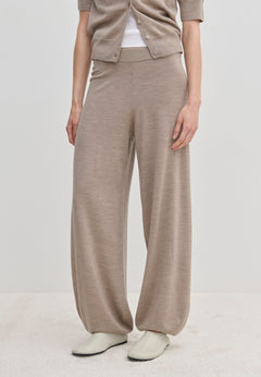 A person wears beige Clark Knit Pants and a matching cardigan over a white top.