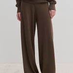 Dark brown Herskind ApS Clark Knit Pants in a relaxed fit, paired with a matching long-sleeved top and black pointed-toe shoes.