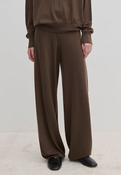 Dark brown Herskind ApS Clark Knit Pants in a relaxed fit, paired with a matching long-sleeved top and black pointed-toe shoes.