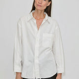A person wearing a white, relaxed fit Lorenzo Shirt by Herskind ApS featuring a point collar and a chest pocket.