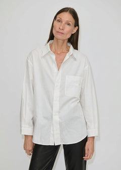 A person wearing a white, relaxed fit Lorenzo Shirt by Herskind ApS featuring a point collar and a chest pocket.