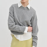 A model wears a grey Constantine Cashmere Knit Blouse by Herskind ApS over a white collared shirt and a pale yellow skirt.