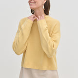 A person wearing a yellow Constantine Cashmere Knit Blouse featuring a crew-neck, long sleeves, and a ribbed hem.