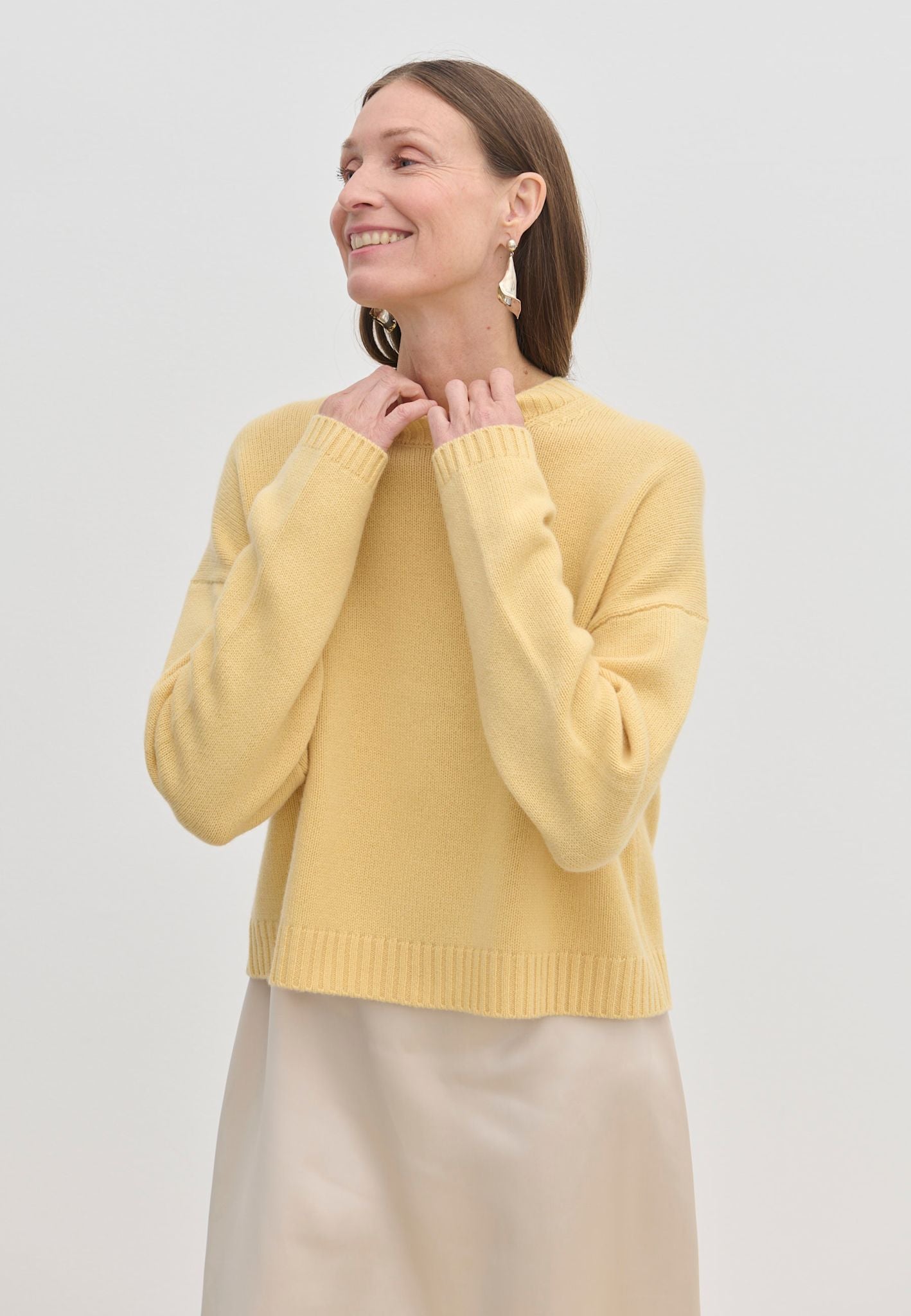 A person wearing a yellow Constantine Cashmere Knit Blouse featuring a crew-neck, long sleeves, and a ribbed hem.