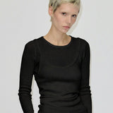 A person wearing a black, slim-fit Petit Knit Top by Herskind ApS, featuring a scoop neckline made from merino wool.
