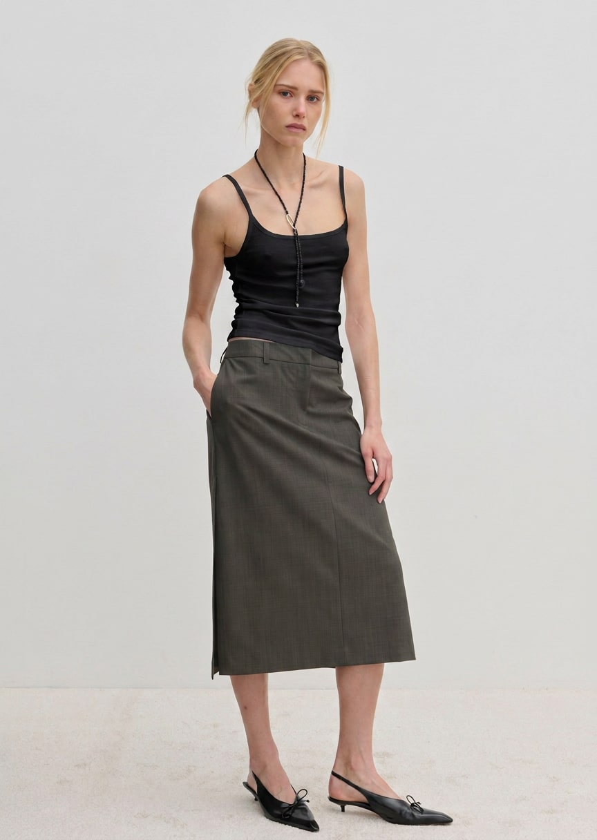 A person wearing a Poppy Top organic cotton slim fit tank top, a dark gray midi skirt, and black slingback kitten heels.