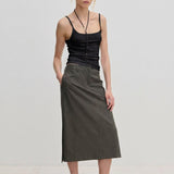 A person wearing a Poppy Top organic cotton slim fit tank top, a dark gray midi skirt, and black slingback kitten heels.
