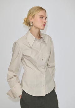 A slim fit, beige Vivienne Shirt by Herskind ApS featuring long sleeves and a pointed collar, paired with dark grey trousers.