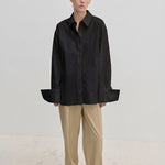 A person wearing an oversized Oeko-Tex cotton Inga Shirt by Herskind ApS with wide cuffs and tan trousers.