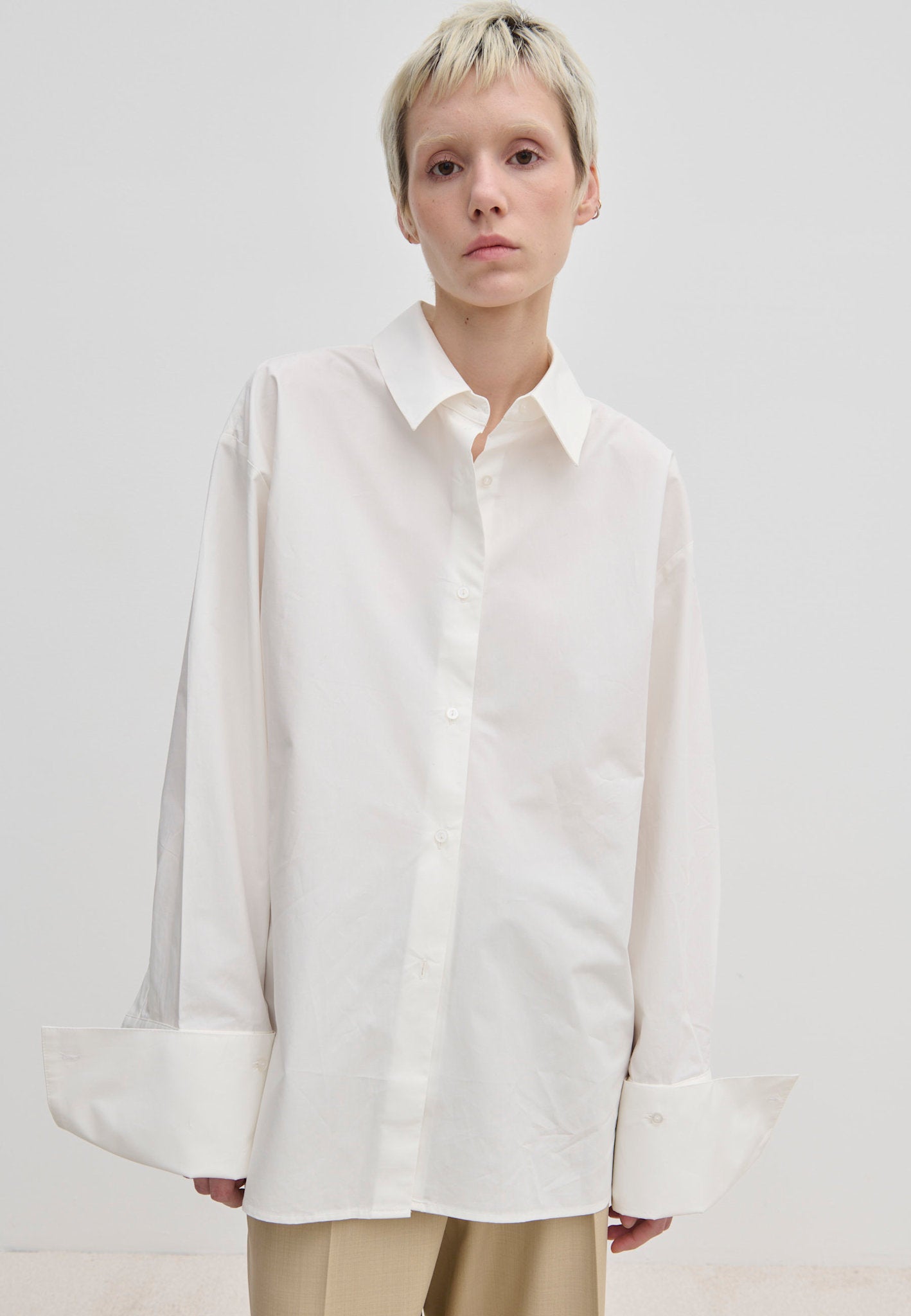 A model wears the Herskind ApS Inga Shirt, a crisp, oversized white button-down with a point collar and wide, folded cuffs.