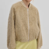 A relaxed fit, beige fuzzy Jimi Bomber Jacket by Herskind ApS with a front zipper, worn over a pale yellow skirt.