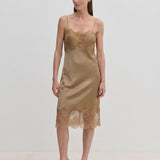 A tan midi-length Herskind ApS Linus Dress with lace-trimmed hem and neckline, worn with pointed-toe heels.
