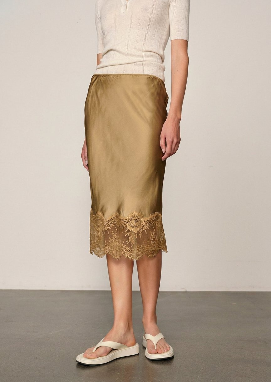 Olive green Herbert Skirt midi slip skirt by Herskind ApS with a wide lace hem, worn with a white top and sandals.