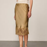 Olive green Herbert Skirt midi slip skirt by Herskind ApS with a wide lace hem, worn with a white top and sandals.